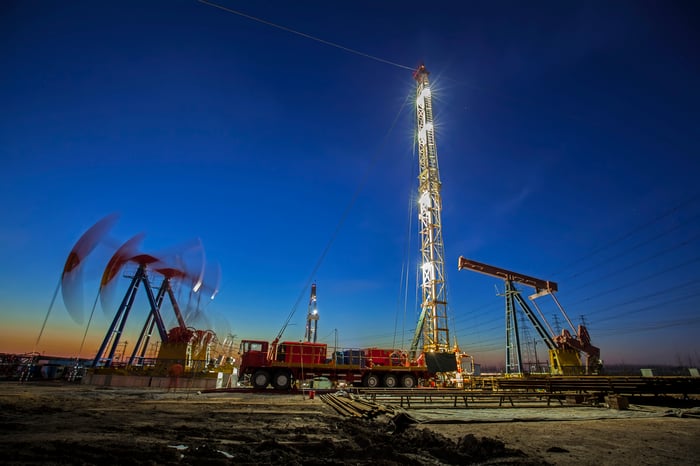 Oil pumps working the the background near a drilling rig.