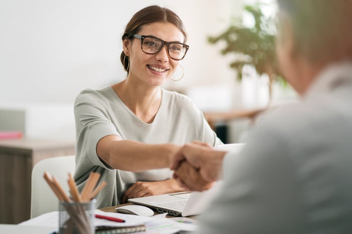 Woman shaking hands with man across the table