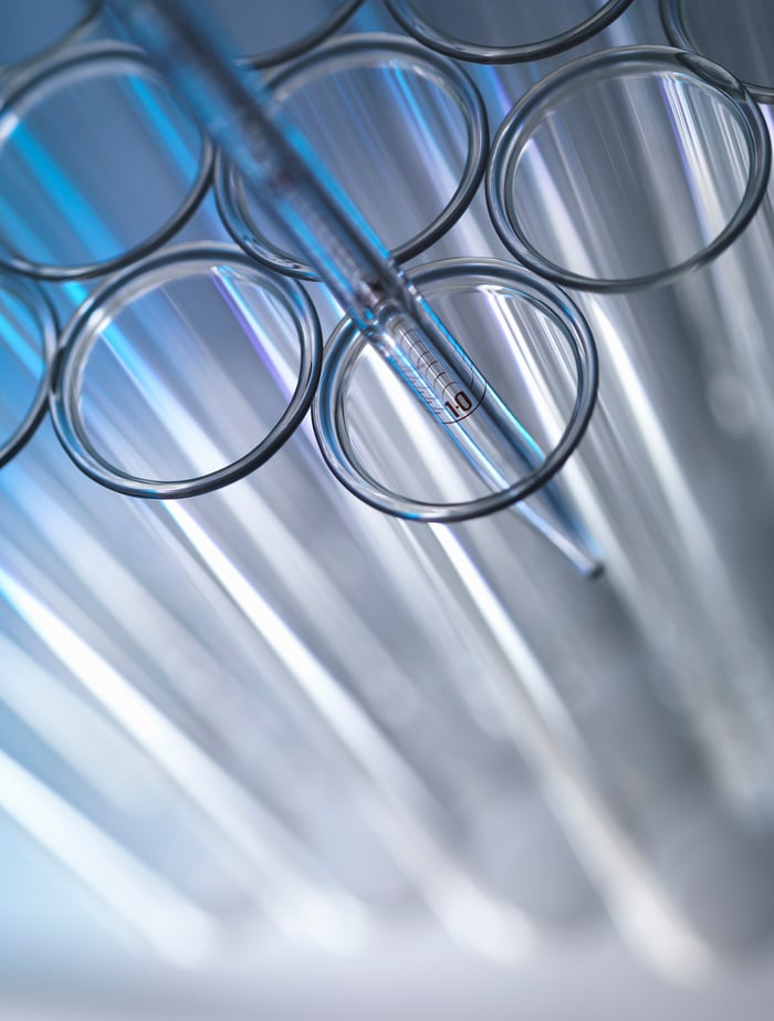 A group of test tubes, with a syringe being dipped inside one