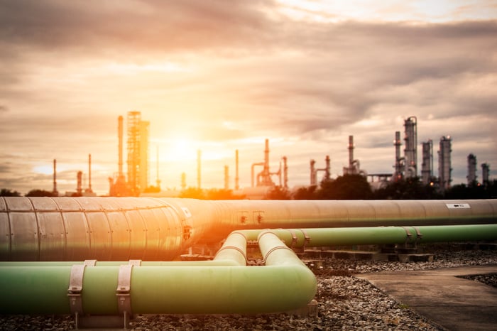 Pipelines heading to a refinery with the sun setting in the background