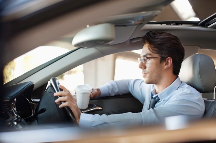 Man driving car while holding to-go cup