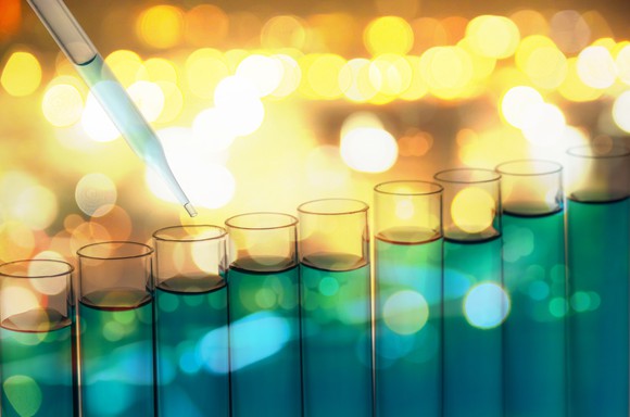 A line of test tubes, with a dropper hovering over one of them.