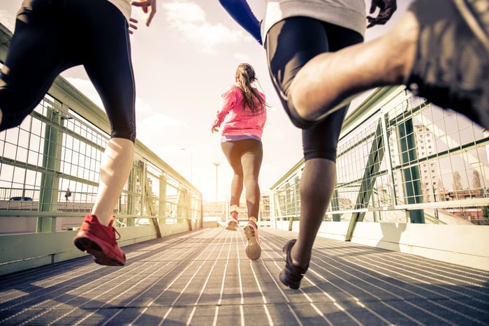 Three people jogging across a foot bridge.