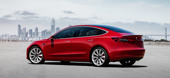 A red Tesla Model 3, a sleek compact luxury-sports sedan