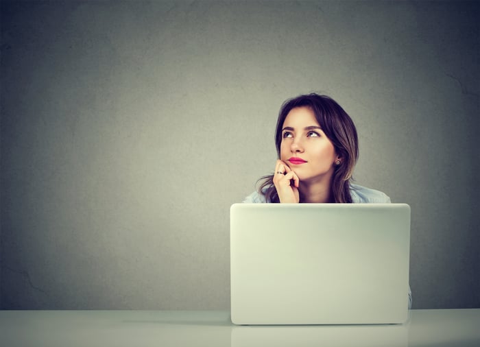 Woman at laptop looking up and off to the side.