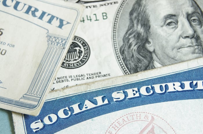 Two Social Security cards partially covering a hundred-dollar bill.