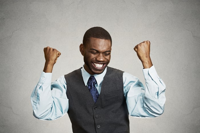 A man pumps his fists in the air while smiling.