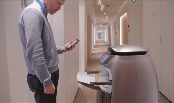 Alibaba's FlyZoo robot is shown bringing an item to a guest in the hotel.