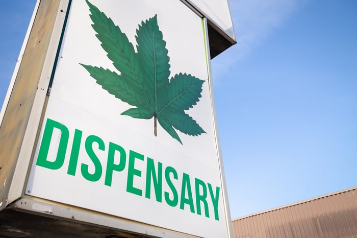 A large sign in front of a cannabis dispensary with a cannabis leaf and the word dispensary underneath it. 