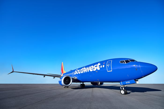 A blue Southwest Airlines 737 MAX 8 on a tarmac under blue skies.