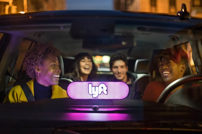 Lighted Lyft logo in windshield with driver and passengers laughing