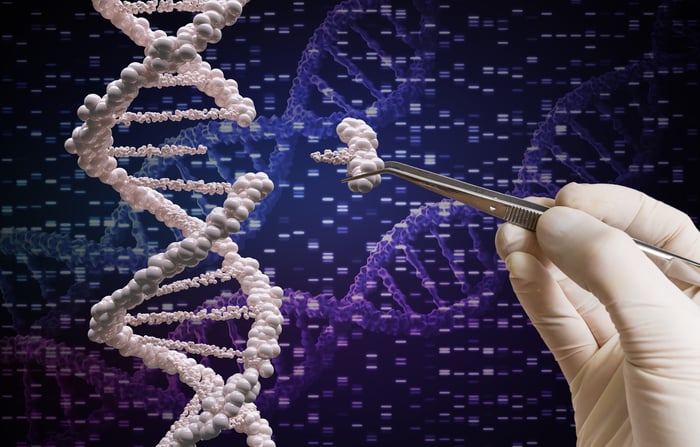 A gloved hand with tweezers removing a nucleotide from a strand of DNA.