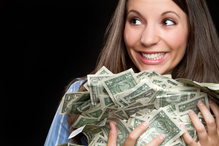 Smiling young woman holding a pile of cash.