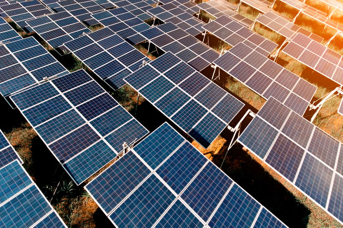 A large solar farm with the sun shining down.