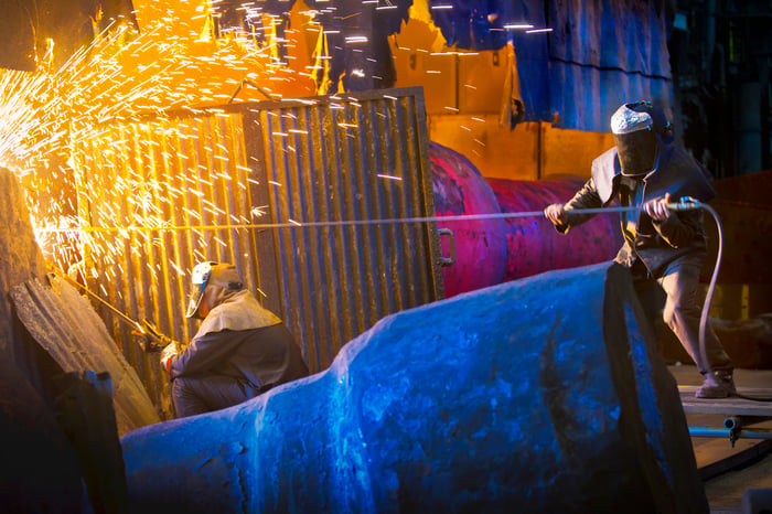 Employees working in a steel mill, with sparks flying around them