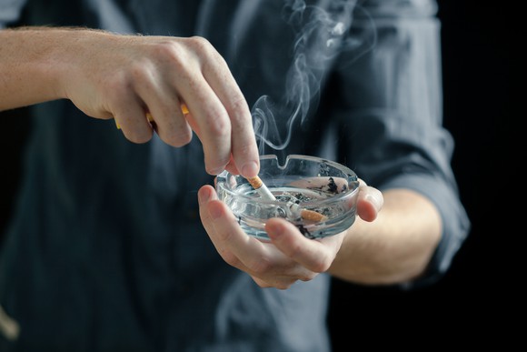 Man stubbing out a cigarette in an ashtray.