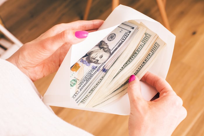 Woman holding envelope full of money.