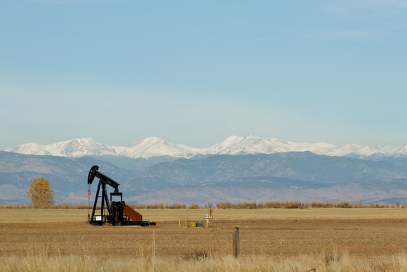 A oil pump with snow-covered mountains in the background.