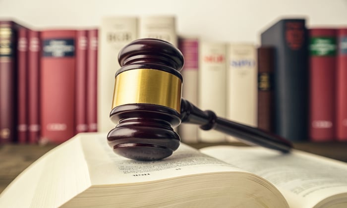 Gavel on an open lawbook on a desk with other books in the background.