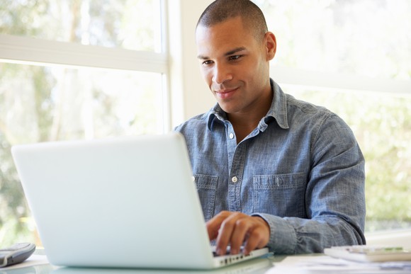 Smiling young male adult at laptop