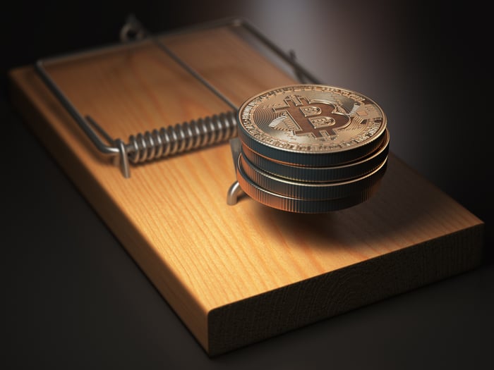 A handful of stacked physical bitcoins in a mouse trap. 