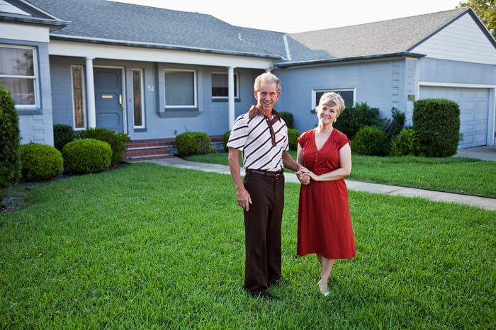 Senior couple standing on front lawn outside home
