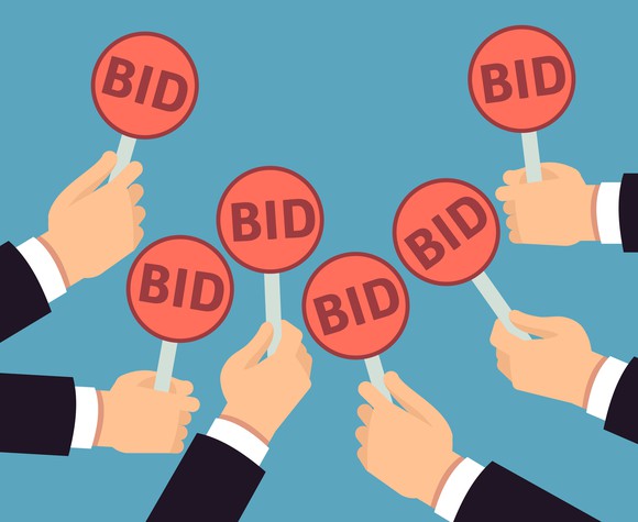 Hands holding up bid signs at an auction