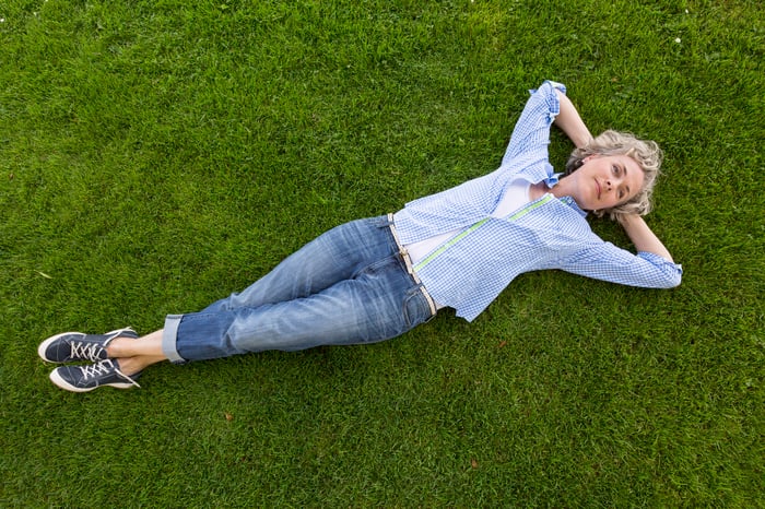 Smiling woman lying down on grass.