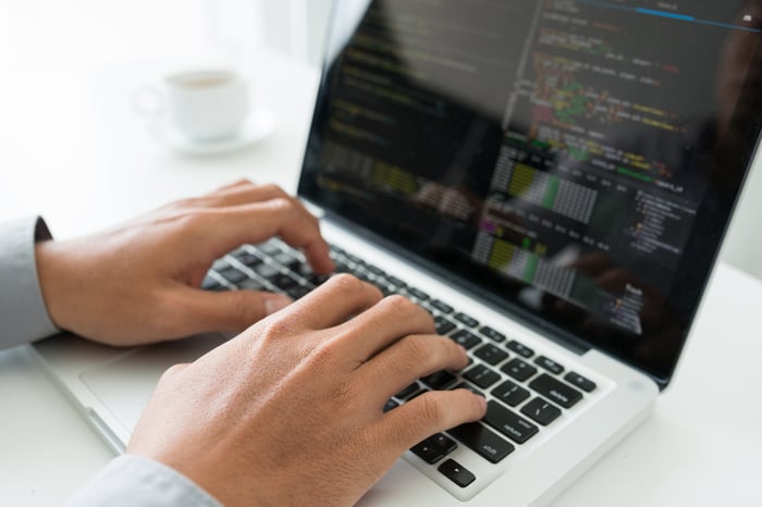 A computer programmer writing code on his laptop. 