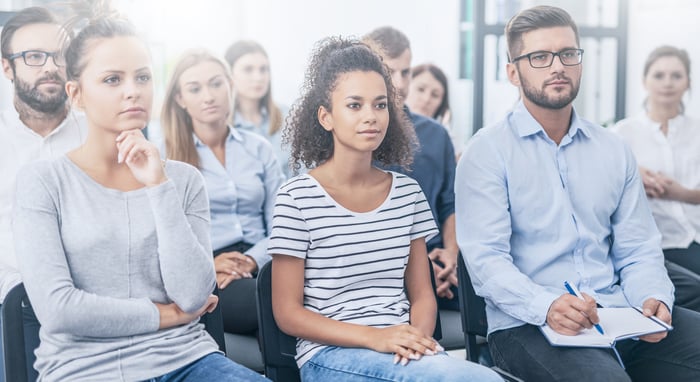A small business team listens to a seminar presentation. A small business team listens to a seminar presentation.