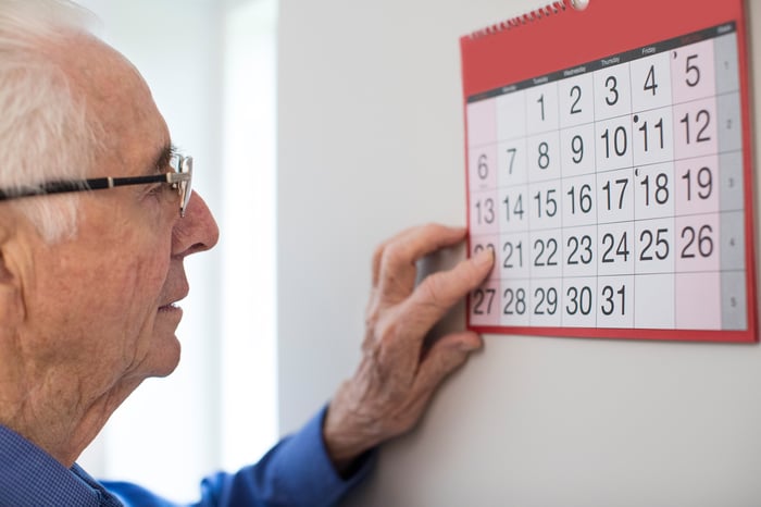 Older man looking at a wall calendar