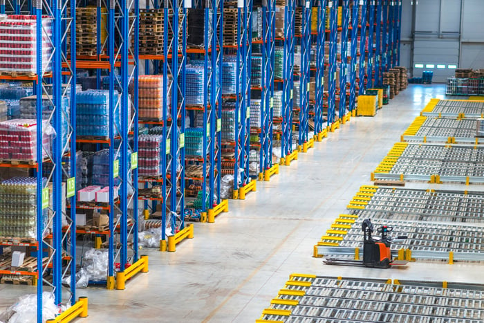 Top view of large storage area in a distribution warehouse interior with goods on the shelf and forklifts