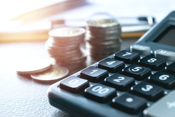 A close-up of a calculator with stacks of coins next to it.