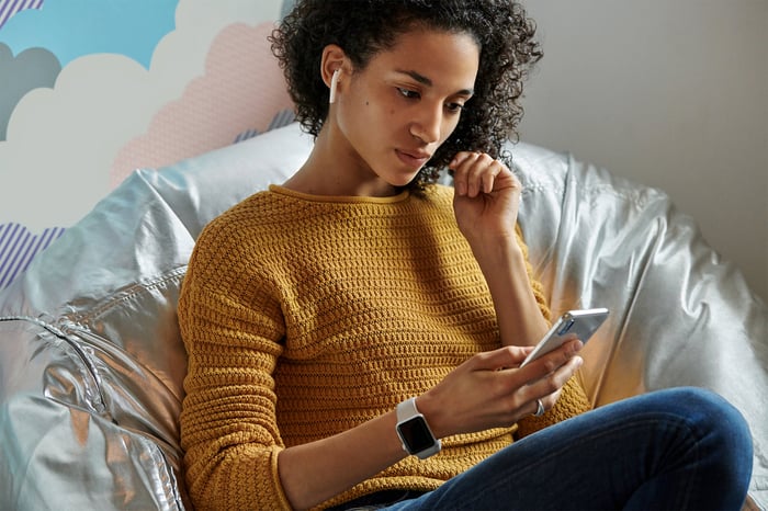 Woman using AirPods, Apple Watch, and an iPhone