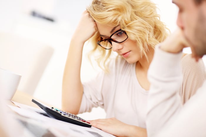 A young woman with glasses using a calculator as she prepares her taxes.