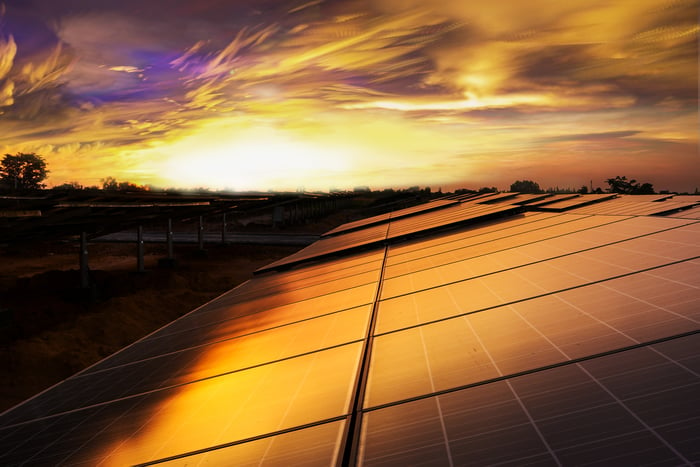 Solar panels on a rooftop with the sun setting in the background.