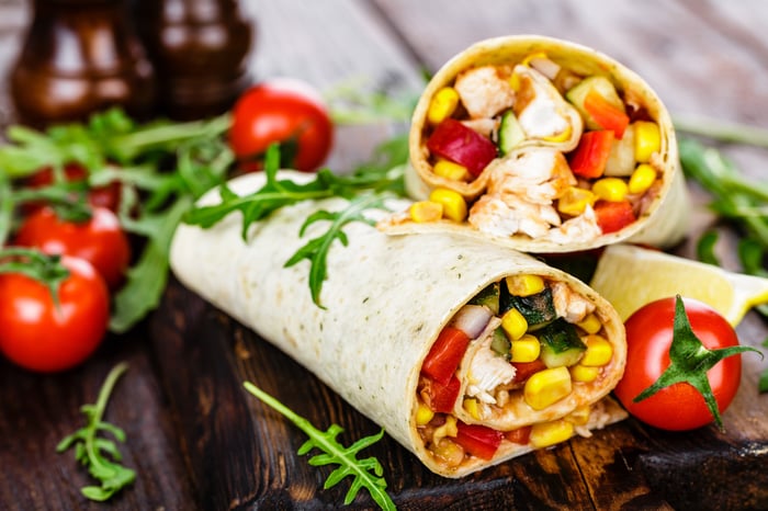 Burrito cut in half amid pile of garnish and tomatoes