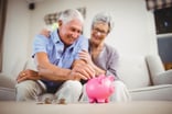 Getty Retirees Putting Money in Piggy Bank