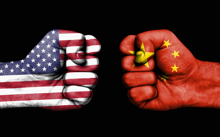 Two fists, one decorated as the American flag, and the other as the Chinese flag, squaring off.