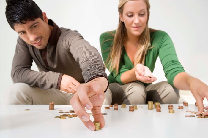 A millennial couple counting coins on a table.
