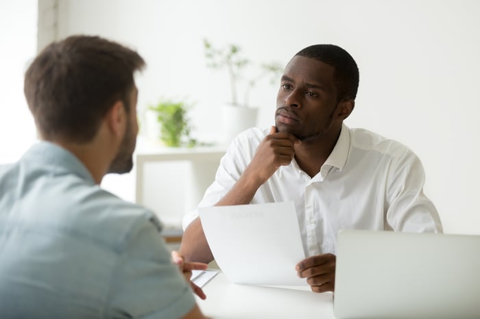 Two men sitting across from each other at desk