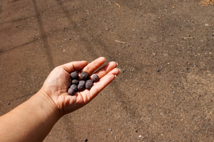 A hand holding iron ore pellets