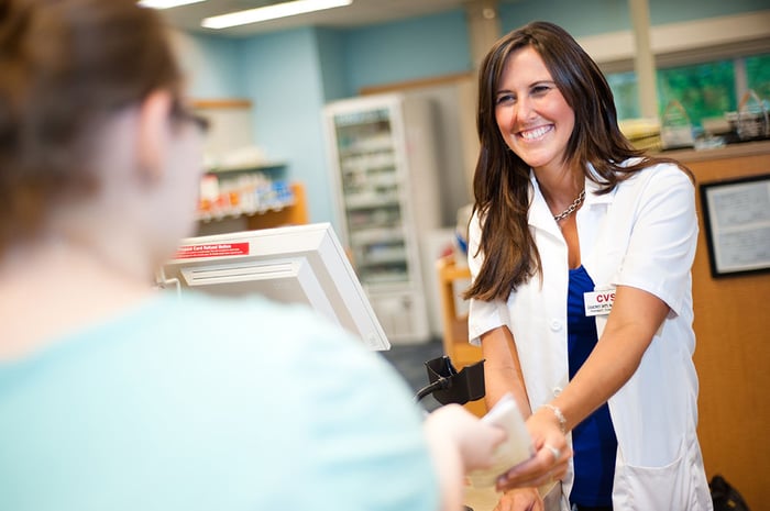 Female CVS pharmacist handing a customer a prescription