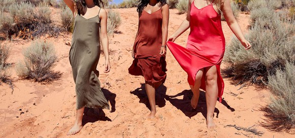 An Aerie ad: Three women wearing slip dresses and walking on sand.