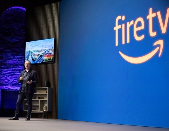 A man on stage with the Fire TV logo projected on a screen.