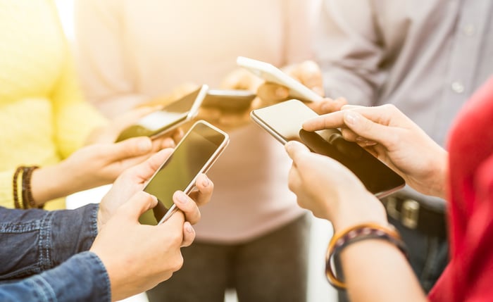 A group of people use their smartphones.