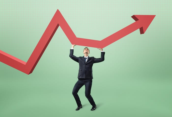 Man in suit supporting a red arrow tilting up