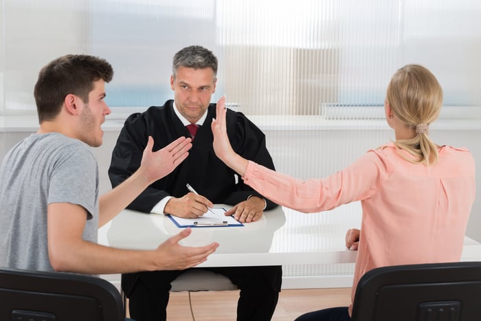 Young husband and wife arguing in front of a judge at a table