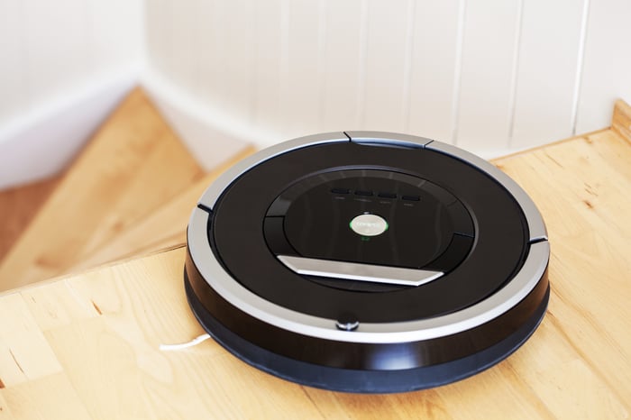 Disc-shaped robot vacuum a the top of a flight of stairs