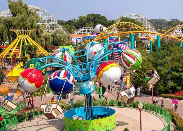 One of Cedar Fair's parks showing a couple smaller rides in foreground and a rollercoaster in the background.